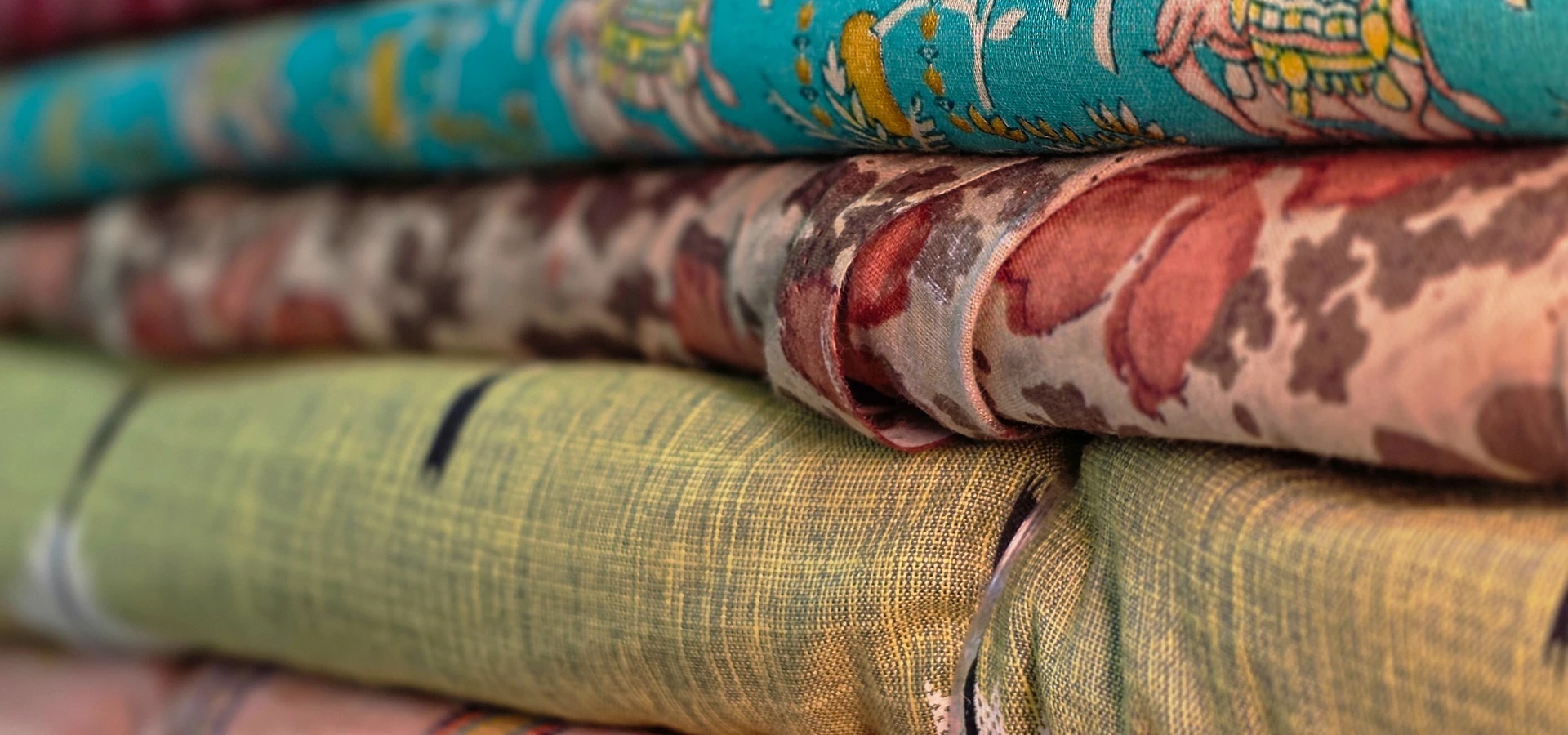 Folded sarees resting on a wooden table in the Savitur showroom